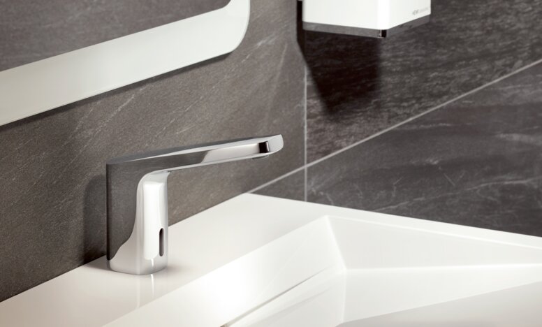 Touchless, chrome-plated mixer tap on a white washbasin