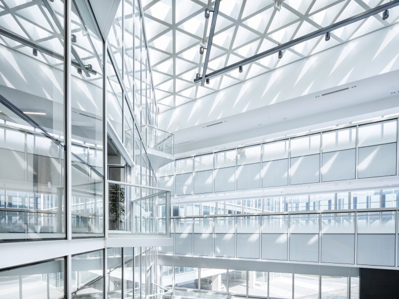 Interior shot of a multi-storey building corridor with bright daylight, balconies and railings